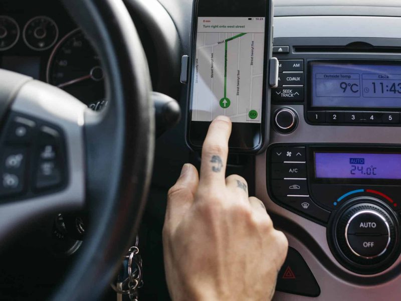 Close-up of man with tattooed hand driving car using cell phone as navigation system Close-up of man with tattooed hand driving car using cell phone as navigation system